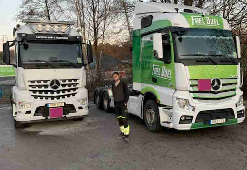 Olof från Larssons Gräv & Transport AB mellan två av åkeriets lastbilar. Åkeriet är en av Workifys åkerikunder. 